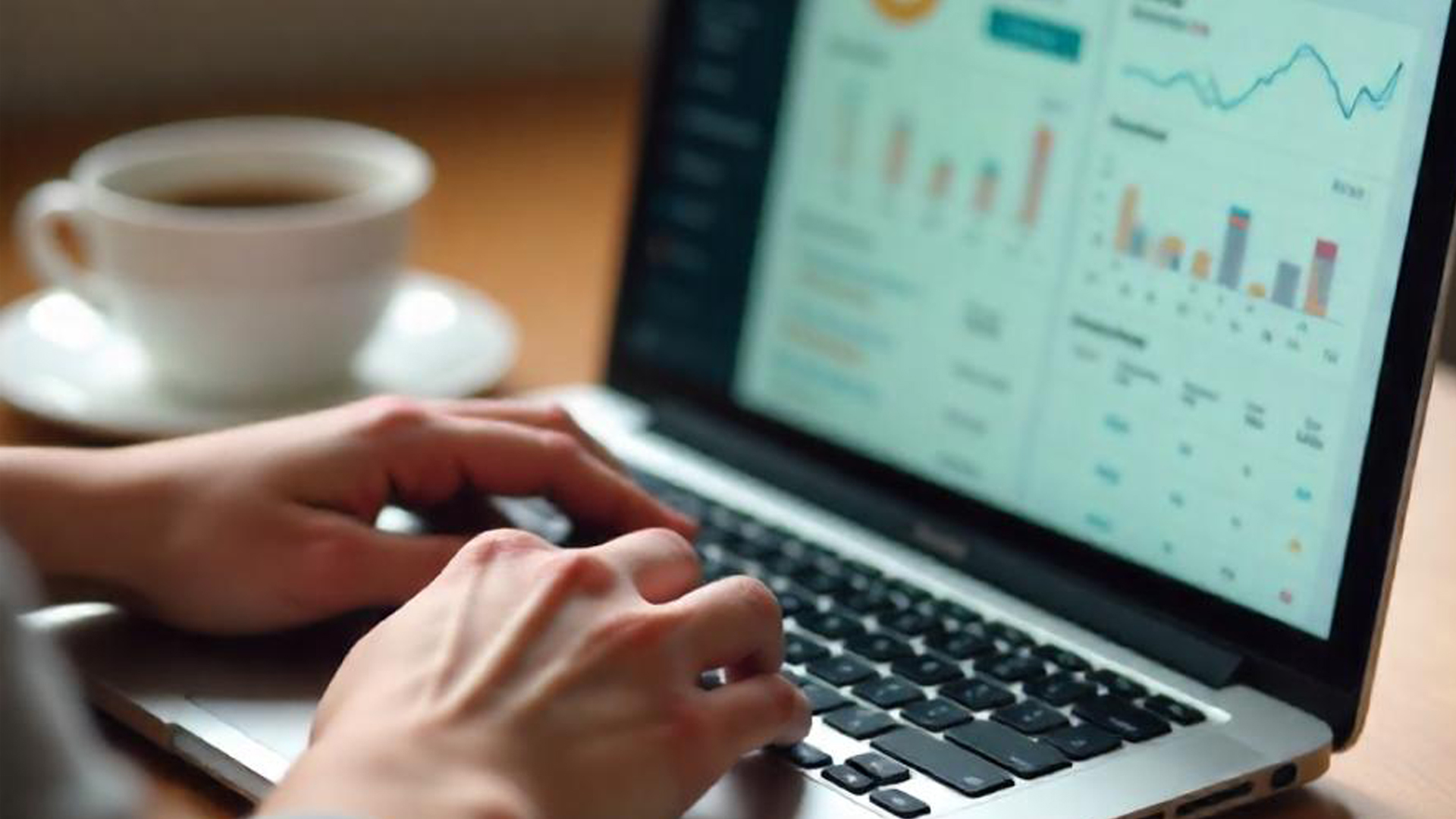 A person typing on a laptop with an analytics dashboard on the screen, exploring ways to earn online. A cup of coffee sits on the wooden table beside them.